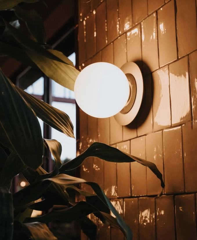 Aplique de pared con esfera opal sobre azulejos esmaltados en cervecería moderna