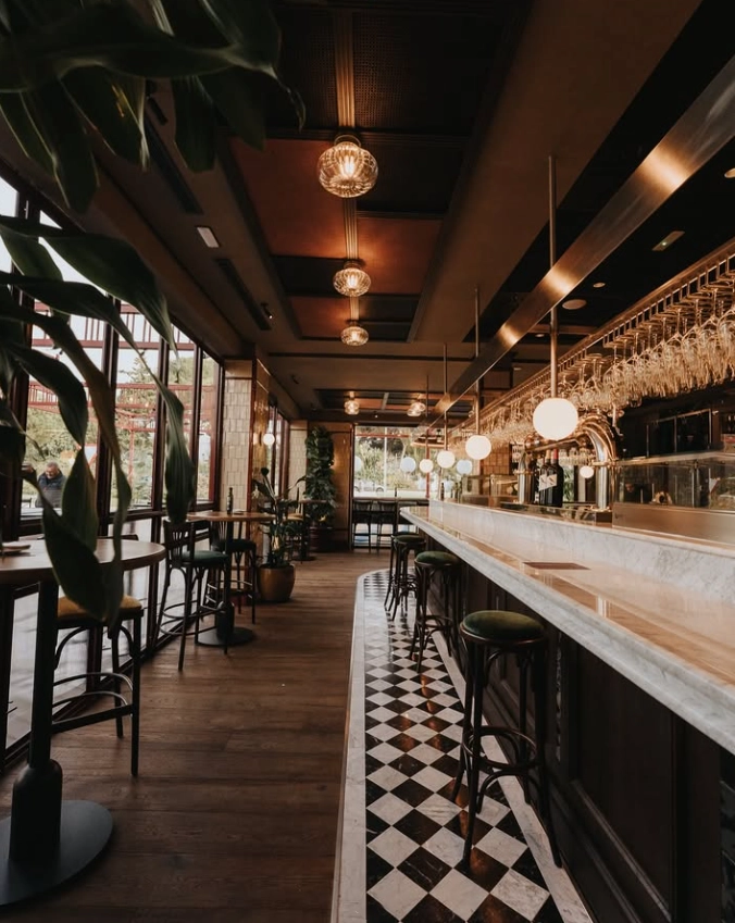 Barra de mármol iluminada con lámparas colgantes de diseño artesanal en La Fenomena