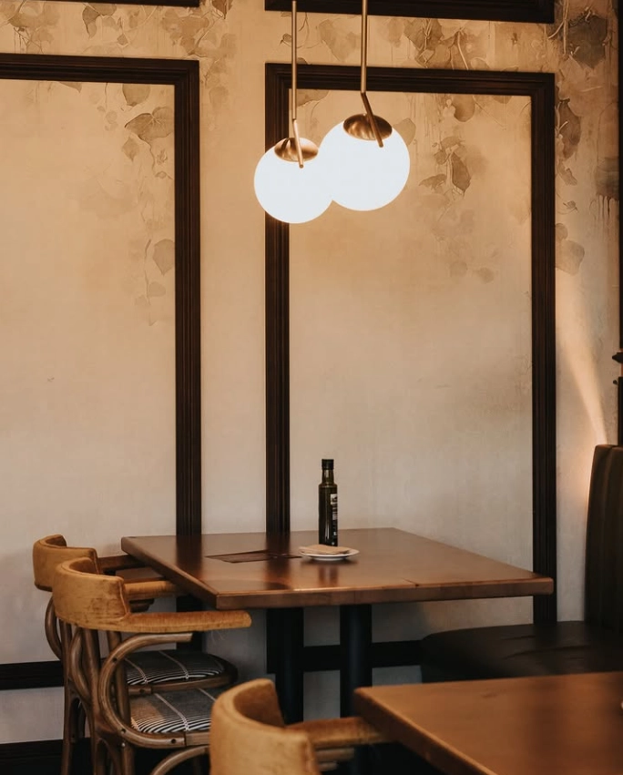 Lámparas colgantes dobles sobre mesas de madera en comedor de estilo retro elegante