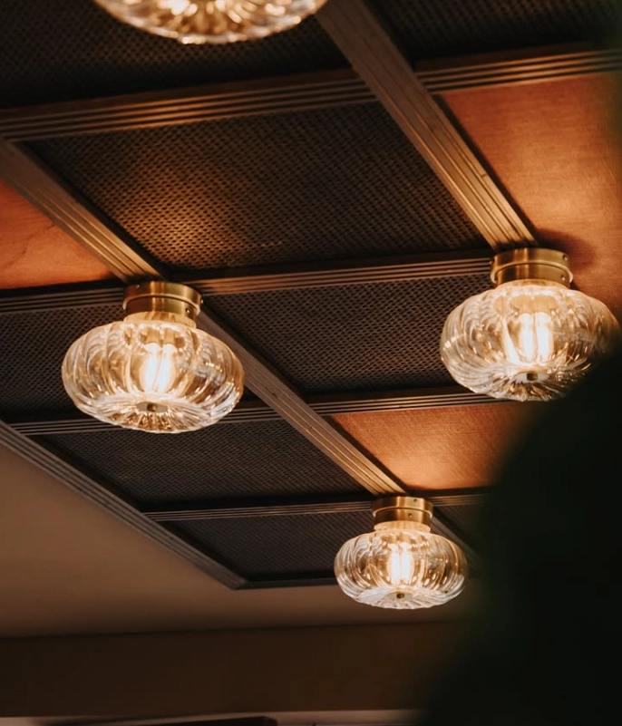 Plafones de techo en cristal transparente con luz cálida en pasillo principal del restaurante