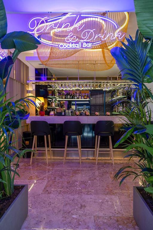 Cocktail bar del Hotel Santa Justa en Lisboa con iluminación artesanal suspendida, neón decorativo, barra elegante y ambiente tropical sofisticado.