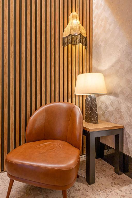 Rincón acogedor del Hotel Santa Justa en Lisboa con sillón de cuero, lámpara artesanal de pared y luz cálida en un ambiente elegante.