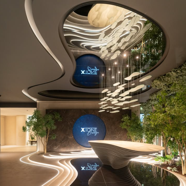 Lobby de XTONE Lounge en Vila-real con luminaria suspendida de cristal artesanal, vegetación interior, iluminación integrada y diseño inspirado en un jardín zen.
