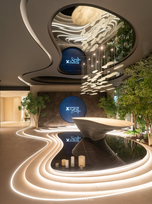 Lobby de XTONE Lounge en Vila-real con luminaria suspendida de cristal artesanal, vegetación interior, iluminación integrada y diseño inspirado en un jardín zen.