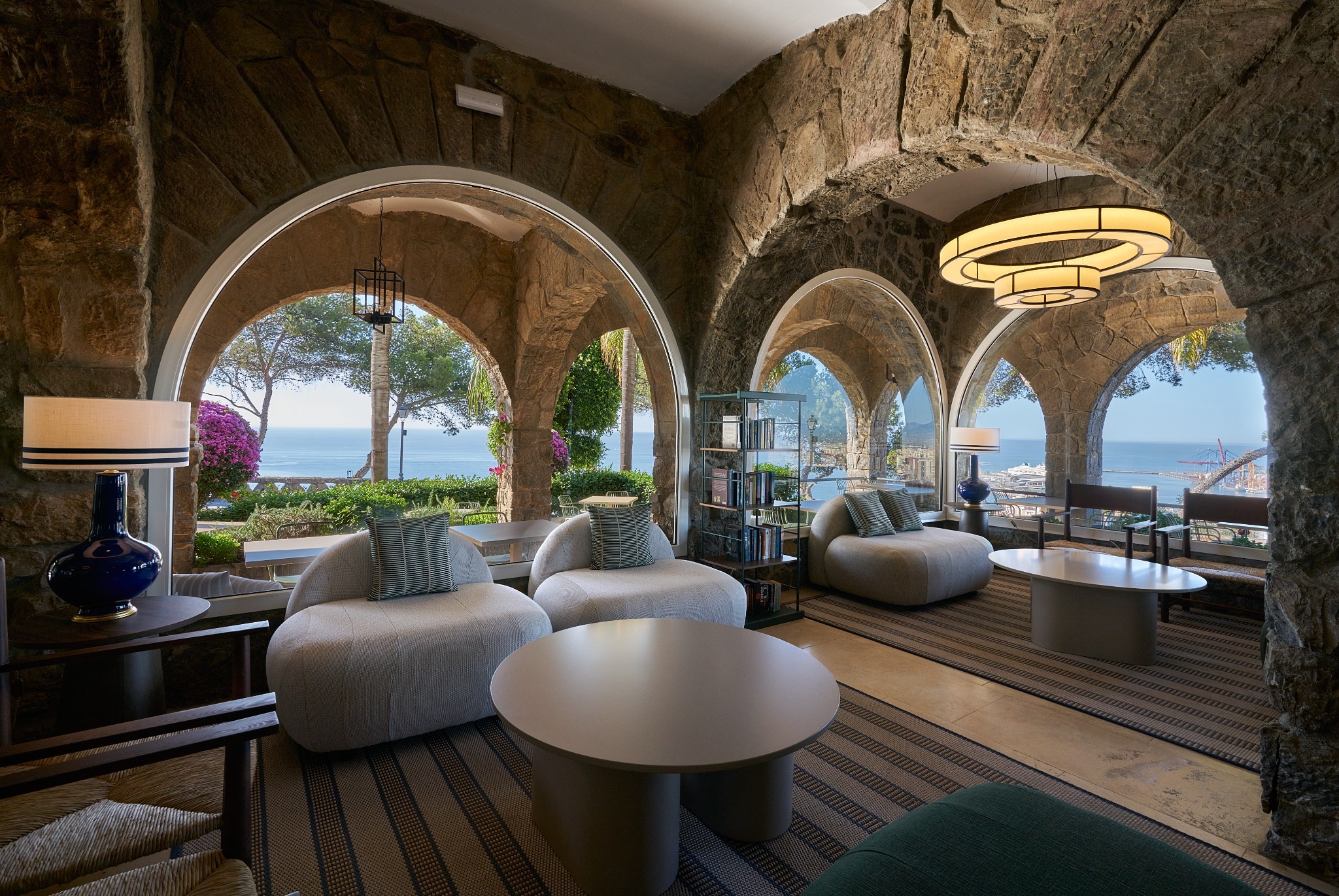 Comedor del Parador de Málaga Gibralfaro con varias lámparas circulares a medida sobre mesas y techo de vigas de madera.
