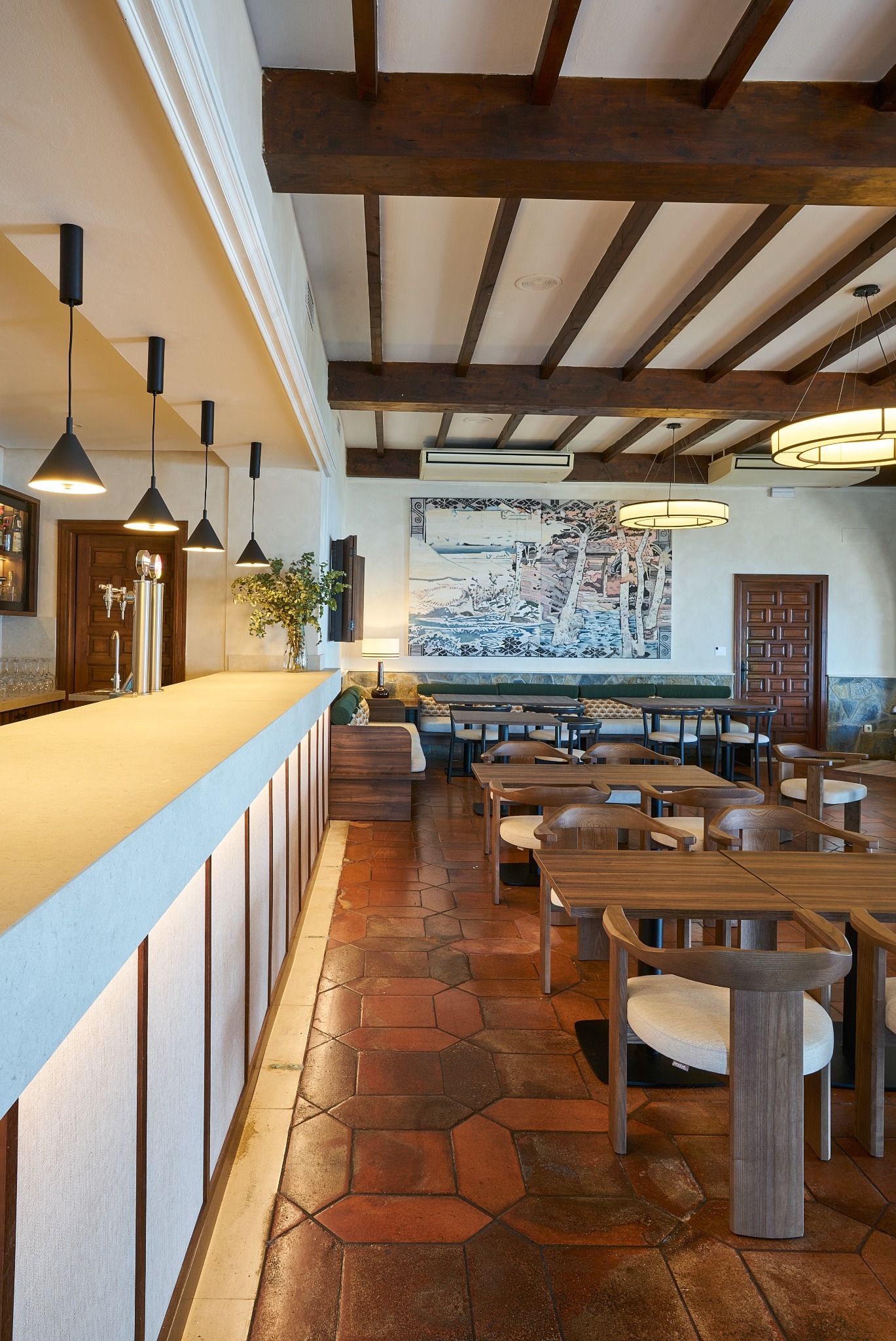 Bar del Parador de Málaga Gibralfaro con lámparas colgantes y lámparas circulares a medida bajo techo de vigas de madera.
