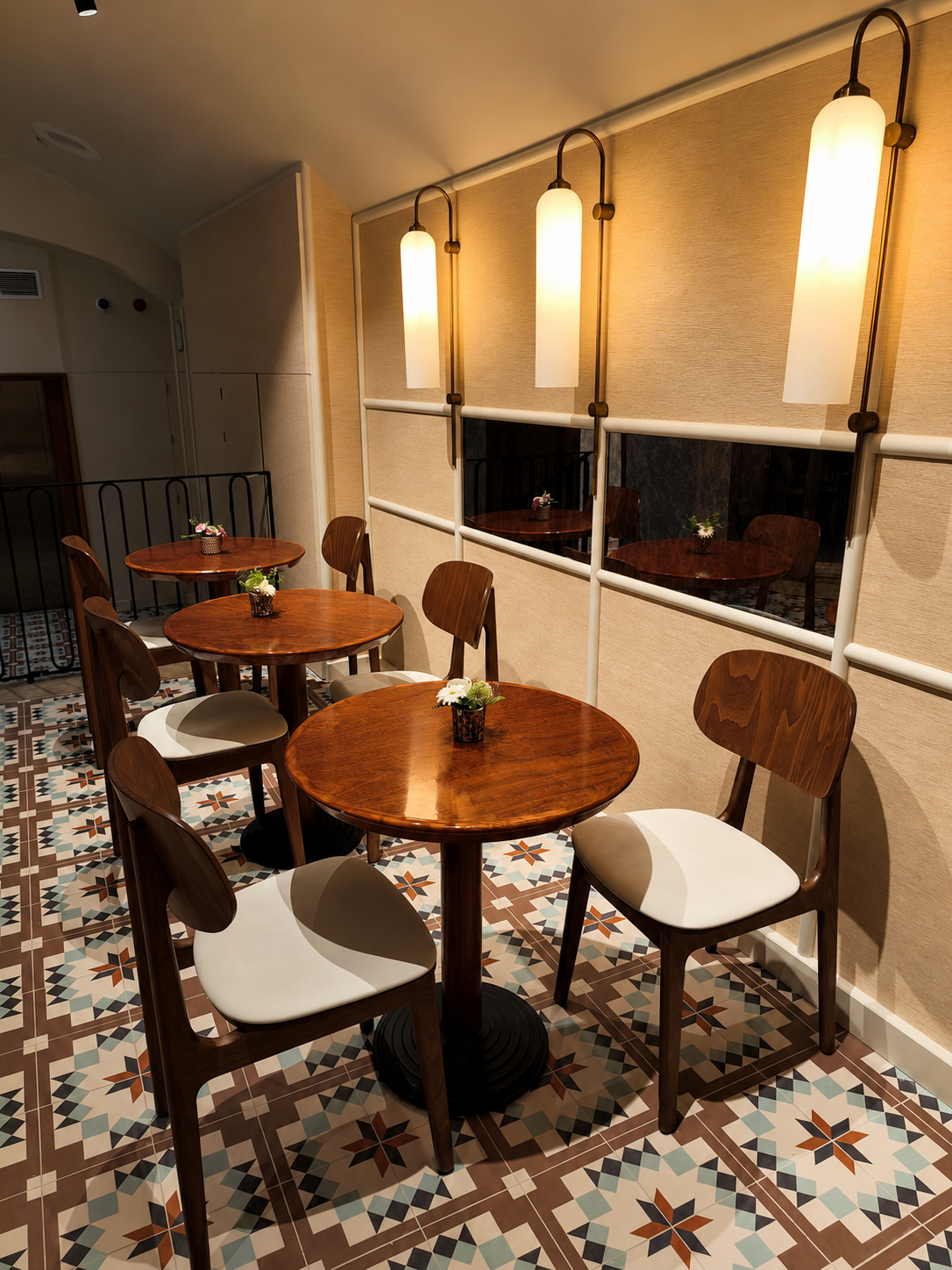 Comedor de hotel con mesas redondas de madera y apliques verticales de cristal