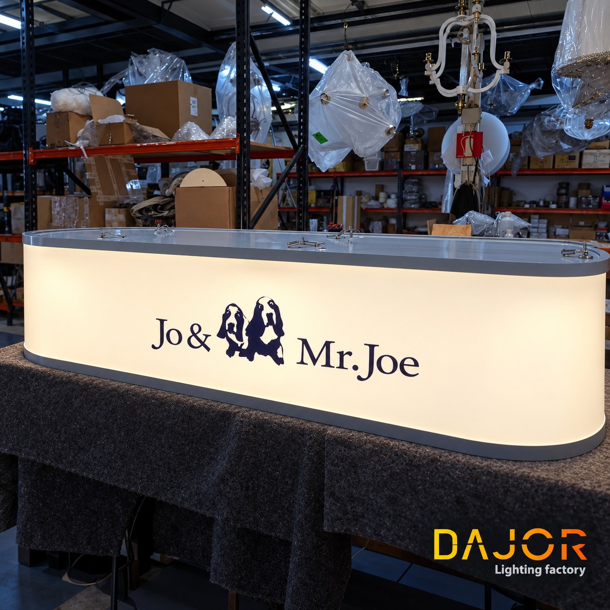 Luminaria de Jo & Mr. Joe encendida sobre una mesa de taller, con el logotipo visible en el frontal.