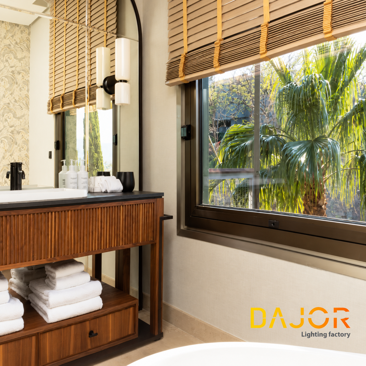 Apliques encendidos de cristal opal sobre un espejo arqueado, junto a un lavabo sobre mueble de madera y una bañera encastrada.